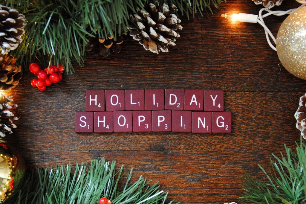 scrabble tiles lined up to say "Holiday Shopping" with christmas decors on the side