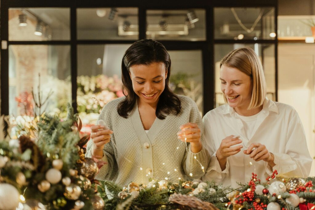two smiling woman holding string lights