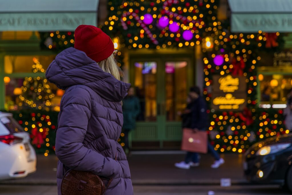 a woman in red knit cap and purple jacket standing on a sidewalk