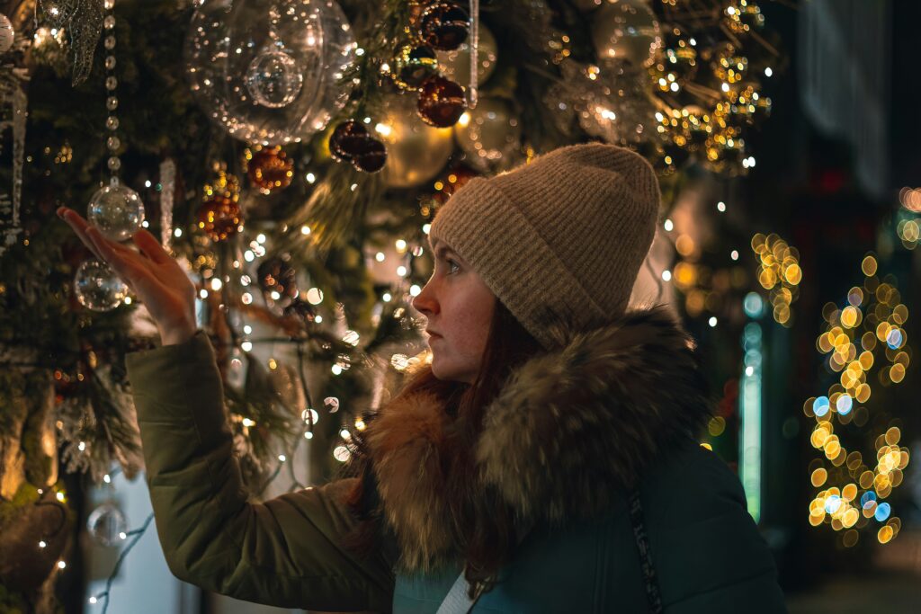a woman touching a christmas ornament on a tree